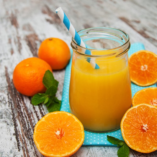 Glass with orange juice on a wooden background